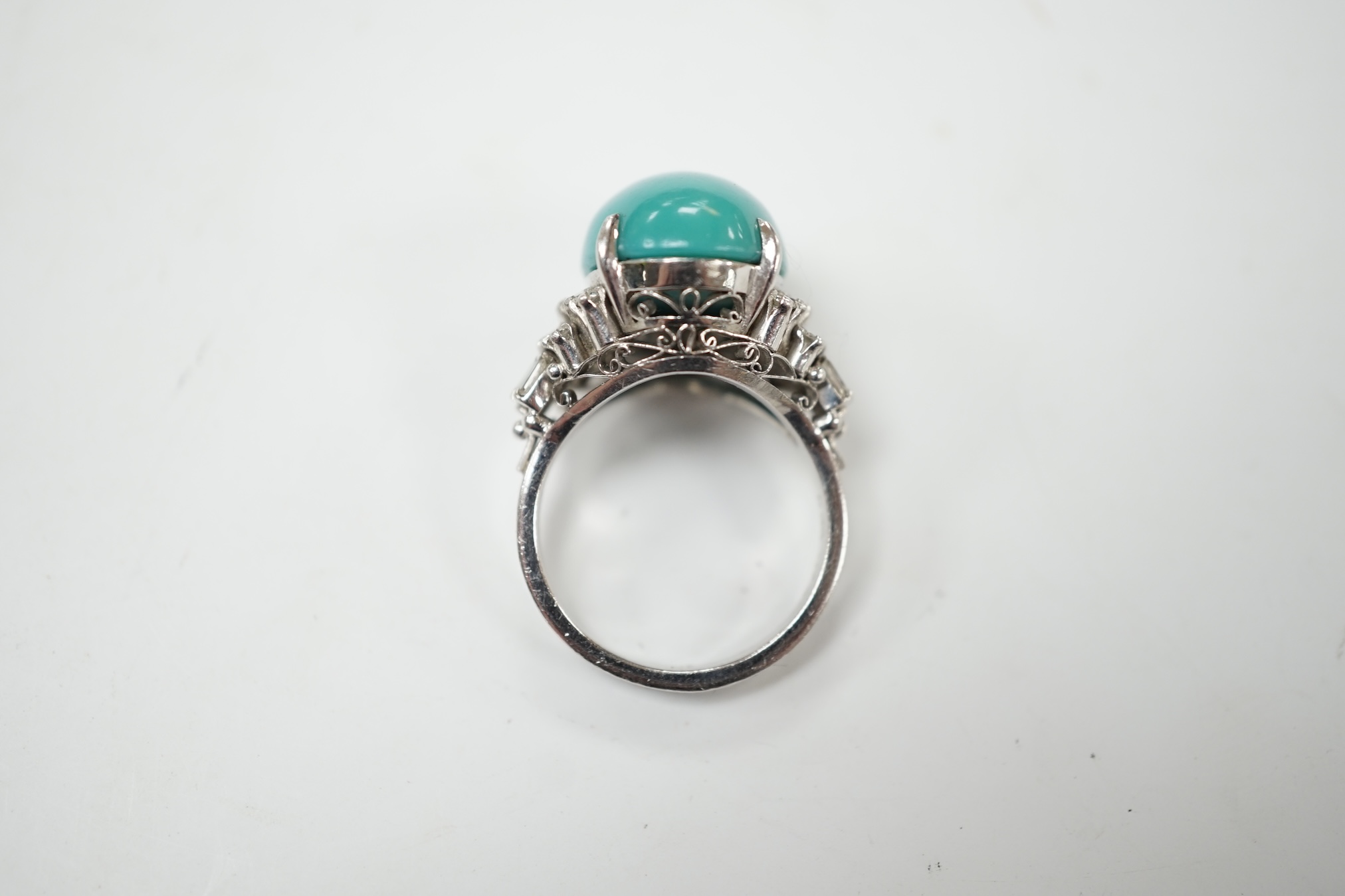 A modern white metal (stamped Pt900) and cabochon turquoise set dress ring, with baguette and round cut diamond set shoulders, size M, gross weight 12.4 grams. Condition - fair